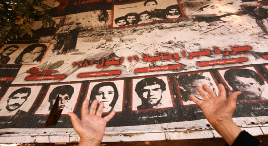  Una anciana palestina reza frente a un póster con fotos de sus parientes asesinados durante una ceremonia conmemorativa en recuerdo de la masacre de Sabra-Shatila en 2010. AFP PHOTO / ANWAR AMOR