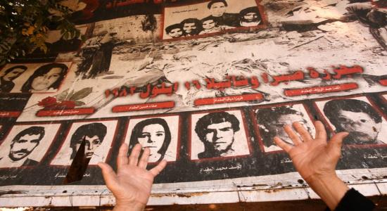  Una anciana palestina reza frente a un póster con fotos de sus parientes asesinados durante una ceremonia conmemorativa en recuerdo de la masacre de Sabra-Shatila en 2010. AFP PHOTO / ANWAR AMOR